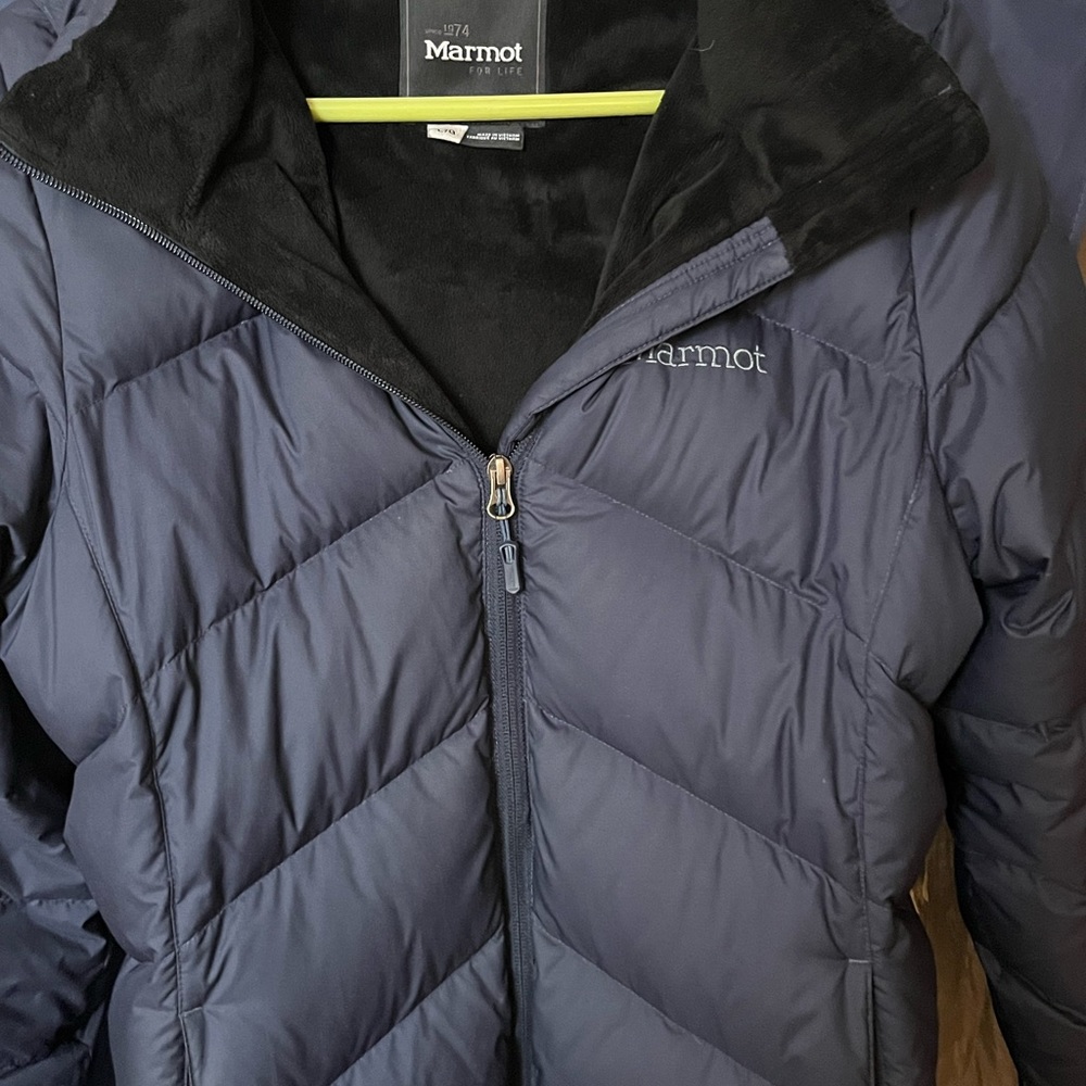 Gently use warm, marmot, long winter coat. Has small tear on bottom left